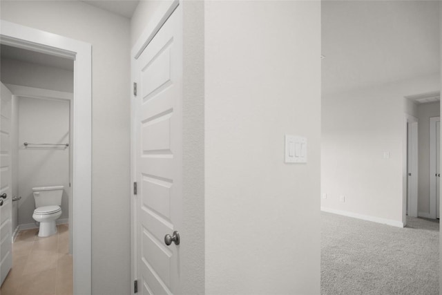 hall with baseboards and light carpet