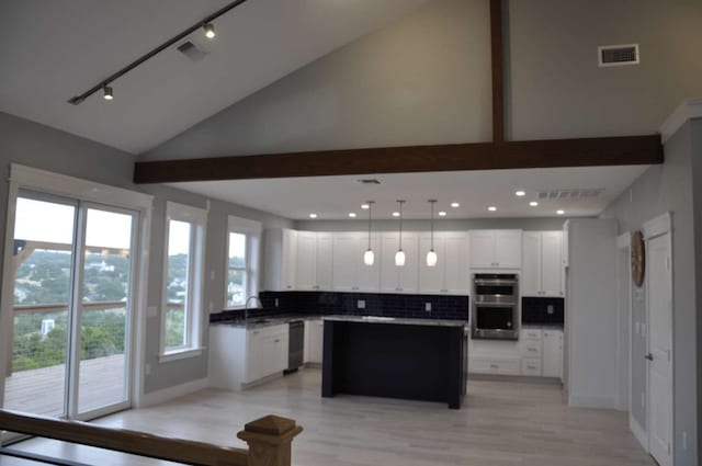 kitchen with stainless steel double oven, rail lighting, tasteful backsplash, decorative light fixtures, and a center island