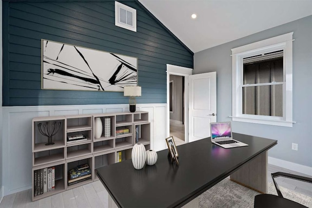 home office with light wood-type flooring, wooden walls, and vaulted ceiling