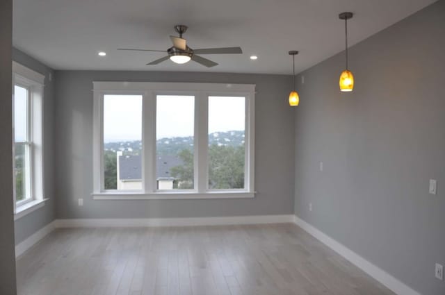 empty room with ceiling fan and light hardwood / wood-style flooring