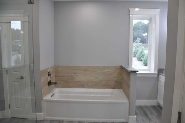 bathroom with a tub, plenty of natural light, and hardwood / wood-style flooring