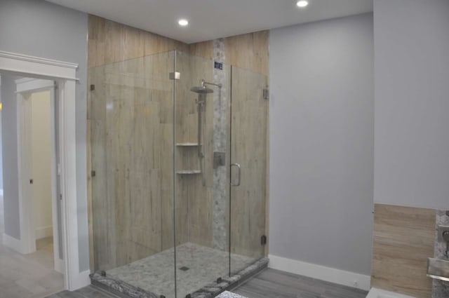 bathroom with a shower with shower door and hardwood / wood-style flooring