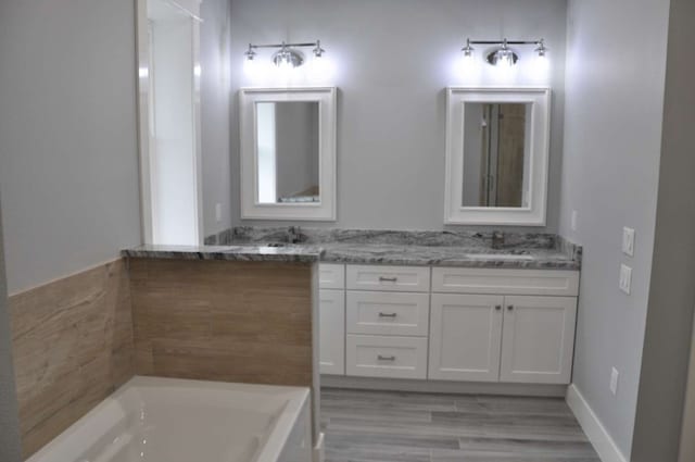 bathroom with dual bowl vanity, hardwood / wood-style floors, and a bath