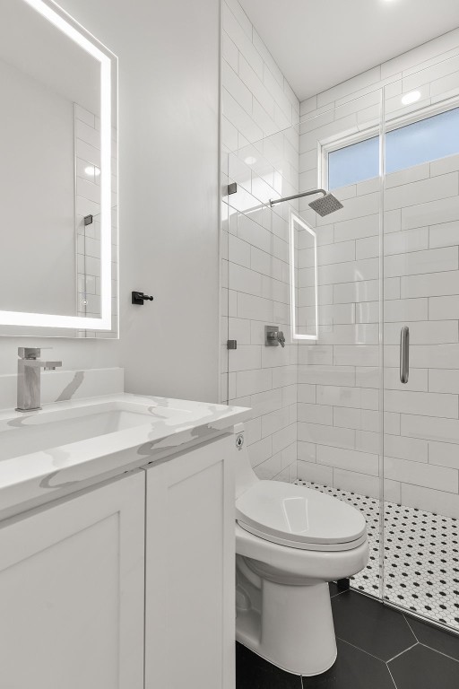 bathroom featuring walk in shower, vanity, toilet, and tile floors