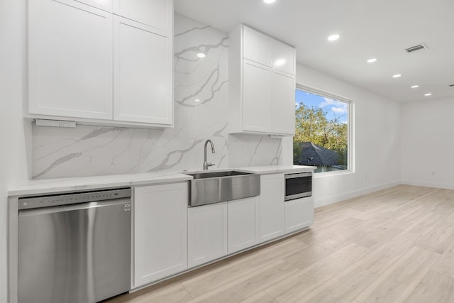 kitchen featuring white cabinetry, stainless steel appliances, light hardwood / wood-style flooring, backsplash, and sink