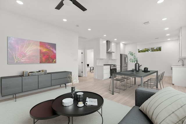 living room with ceiling fan, sink, and light wood-type flooring