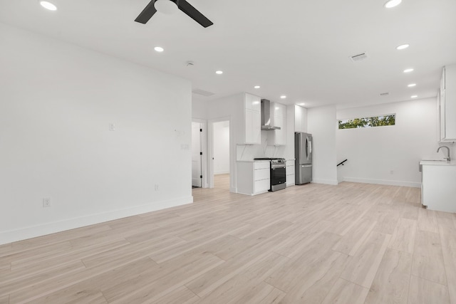 unfurnished living room with ceiling fan, sink, and light hardwood / wood-style flooring