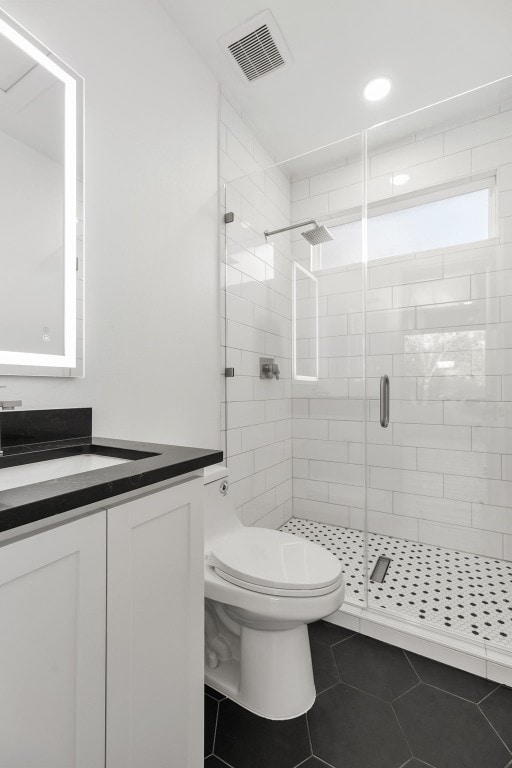 bathroom featuring toilet, a shower with door, tile floors, and vanity