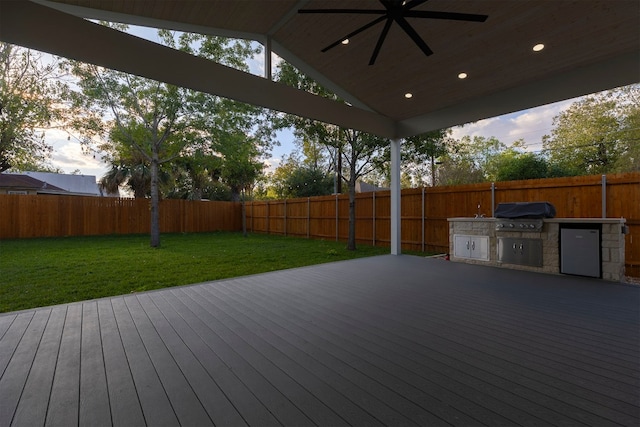 deck featuring a yard, grilling area, and an outdoor kitchen