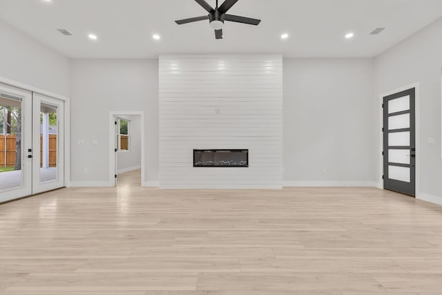 unfurnished living room with french doors, a fireplace, ceiling fan, and light hardwood / wood-style flooring