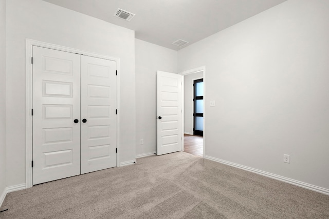 unfurnished bedroom with a closet and light carpet