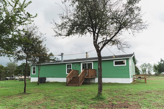 rear view of house with central air condition unit and a yard