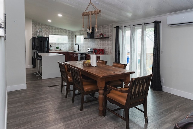 dining space featuring an AC wall unit, lofted ceiling, a notable chandelier, dark hardwood / wood-style flooring, and sink