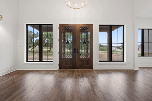 foyer with dark hardwood / wood-style floors, french doors, and a chandelier