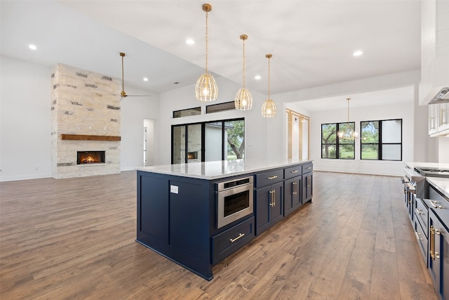 kitchen with a center island, hanging light fixtures, light wood-type flooring, blue cabinetry, and a stone fireplace