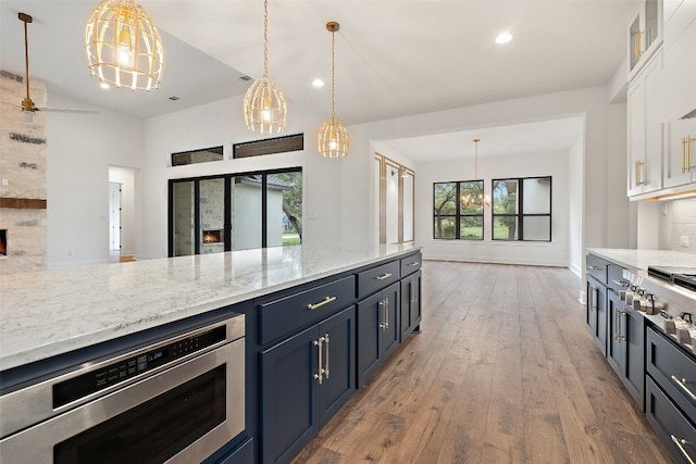 kitchen with white cabinets, dark hardwood / wood-style floors, pendant lighting, and light stone counters