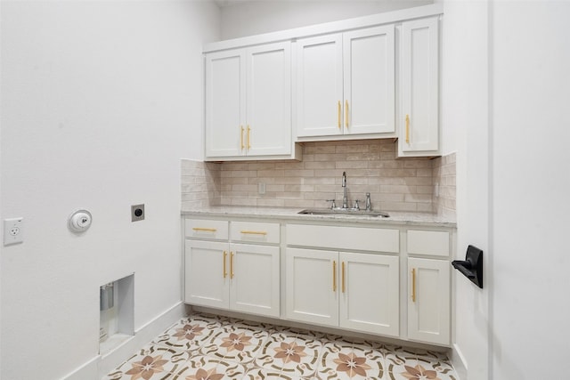 kitchen with light stone countertops, white cabinetry, light tile floors, sink, and tasteful backsplash