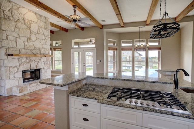 kitchen featuring pendant lighting, white cabinetry, stainless steel gas stovetop, and dark stone countertops