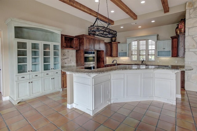 kitchen with double oven, beam ceiling, a sink, and tasteful backsplash