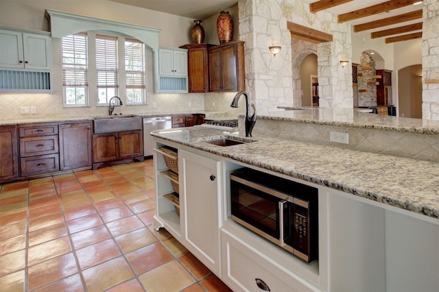 kitchen featuring sink, stainless steel appliances, tasteful backsplash, light stone countertops, and white cabinets