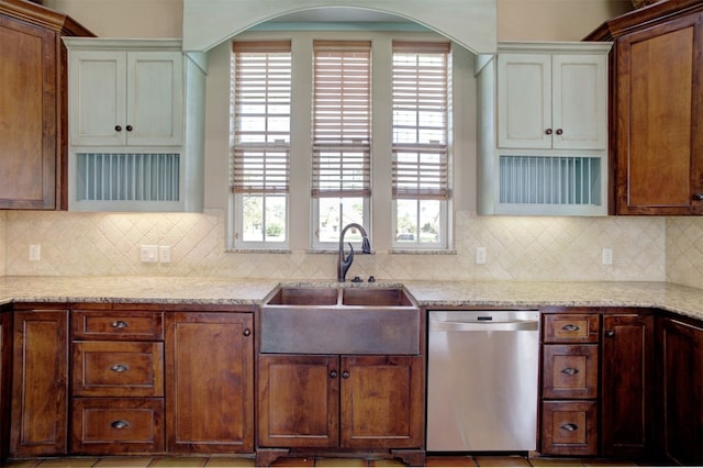 kitchen with light stone countertops, sink, stainless steel dishwasher, and decorative backsplash