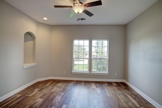 empty room with baseboards, visible vents, dark wood finished floors, and a ceiling fan