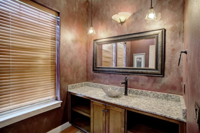 bathroom featuring a textured wall, baseboards, and vanity