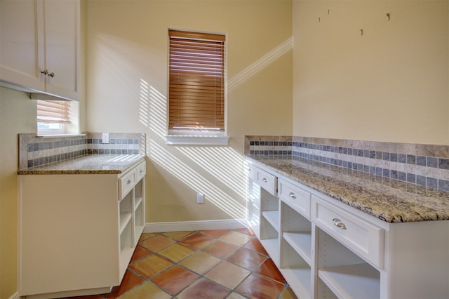 kitchen featuring white cabinetry, light stone countertops, tasteful backsplash, and light tile patterned floors