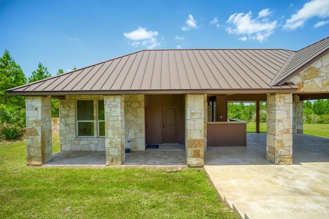 view of front of home featuring driveway, stone siding, metal roof, a standing seam roof, and a front yard