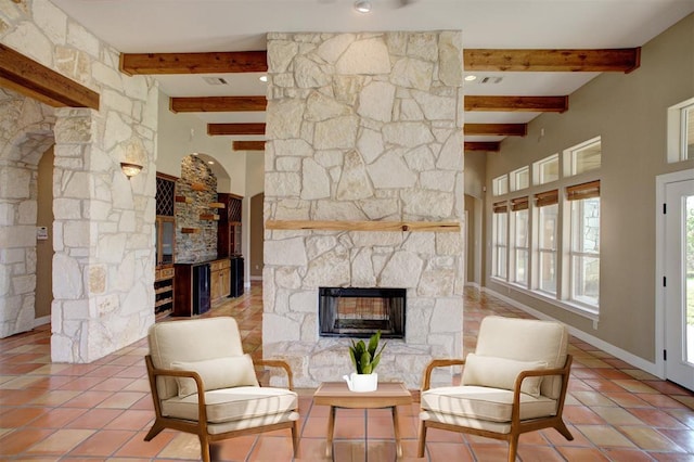 living area featuring tile patterned flooring, a fireplace, and beamed ceiling