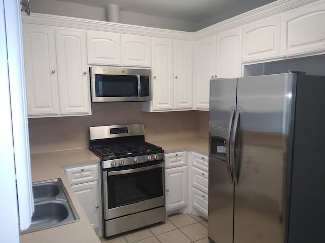 kitchen with white cabinets, appliances with stainless steel finishes, light tile floors, and sink