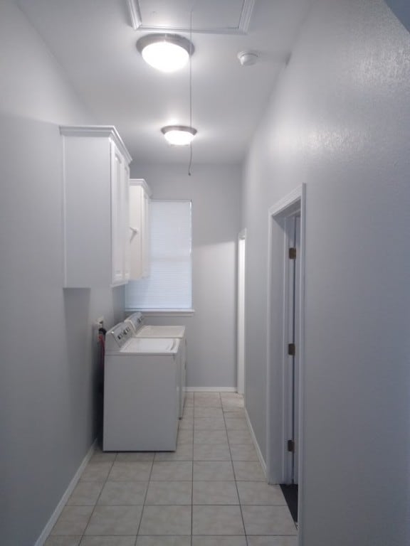 clothes washing area featuring cabinets, light tile floors, and washing machine and dryer