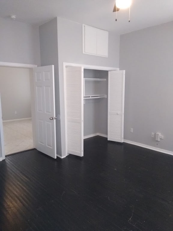 unfurnished bedroom with a closet, ceiling fan, and dark wood-type flooring