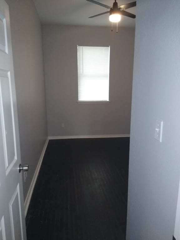 empty room with dark hardwood / wood-style floors and ceiling fan