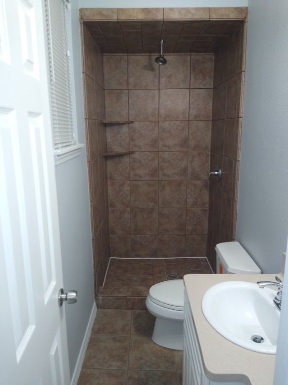 bathroom featuring tile floors, toilet, vanity, and tiled shower