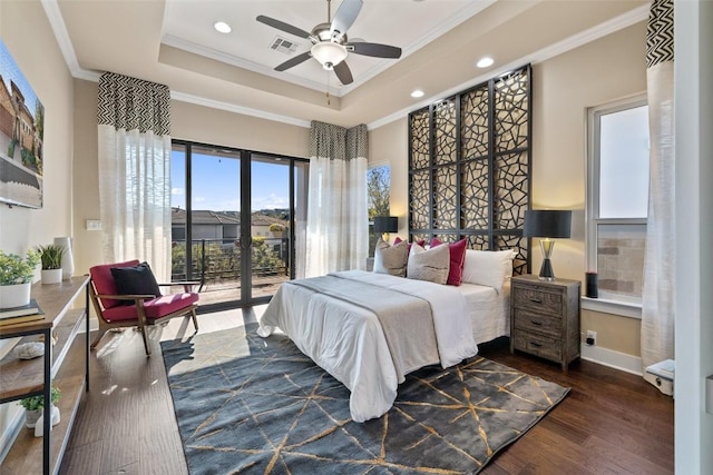 bedroom featuring visible vents, a tray ceiling, dark wood-style flooring, and ornamental molding