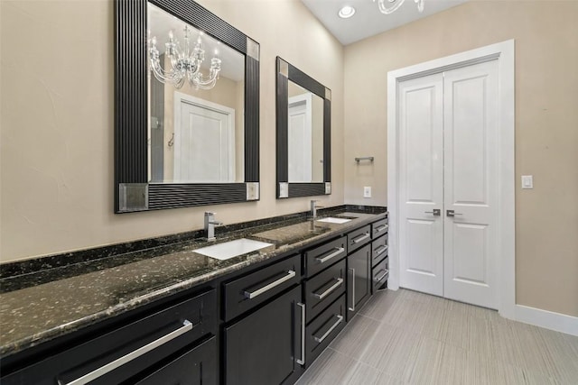 bathroom featuring a closet, a sink, an inviting chandelier, and double vanity