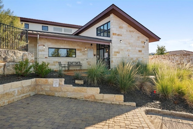 view of front of house featuring stone siding and a patio area