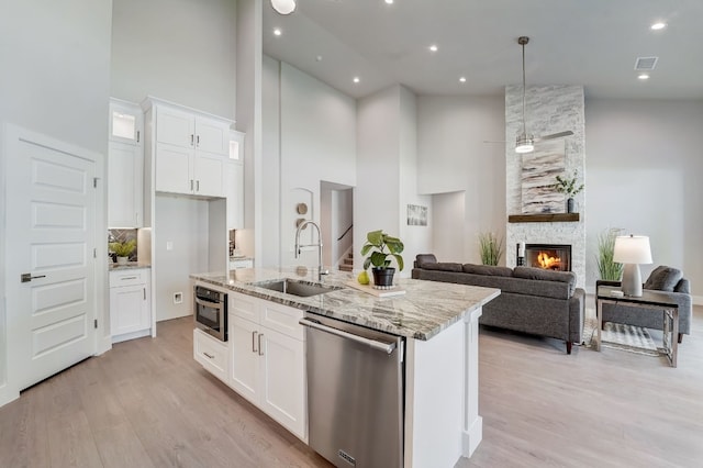 kitchen featuring appliances with stainless steel finishes, a fireplace, sink, high vaulted ceiling, and white cabinets