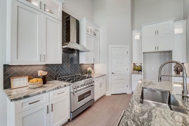 kitchen with white cabinetry, high end stainless steel range oven, and wall chimney exhaust hood