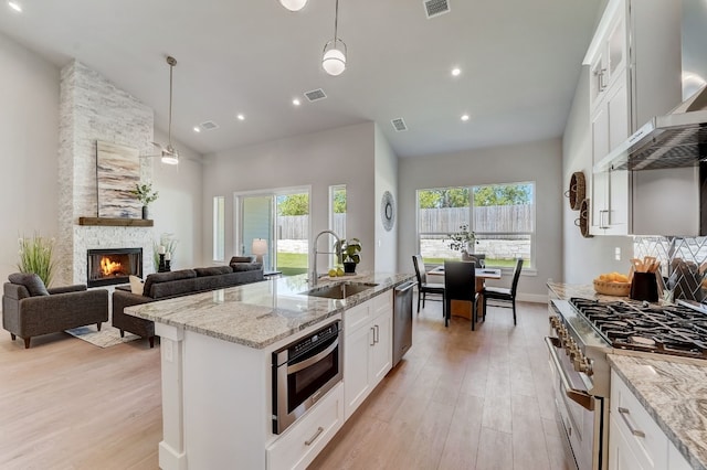 kitchen featuring stainless steel appliances, white cabinetry, hanging light fixtures, and sink