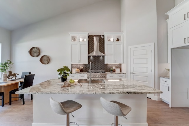 kitchen featuring white cabinets, sink, light hardwood / wood-style floors, and wall chimney range hood