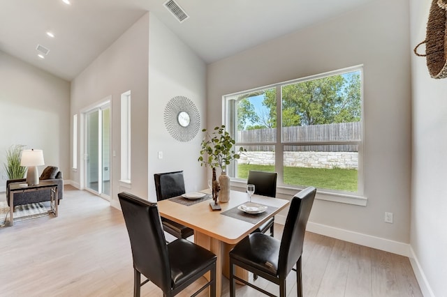 dining room with vaulted ceiling and light hardwood / wood-style flooring