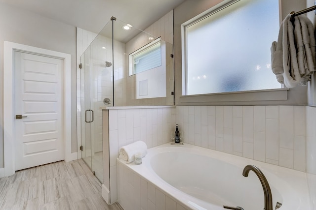 bathroom featuring wood-type flooring and shower with separate bathtub