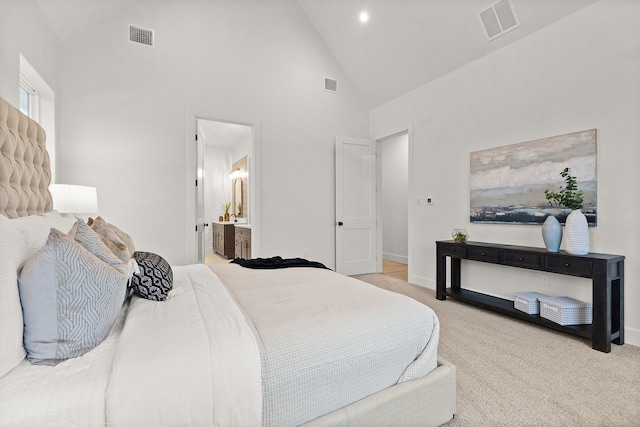 carpeted bedroom with ensuite bathroom and high vaulted ceiling