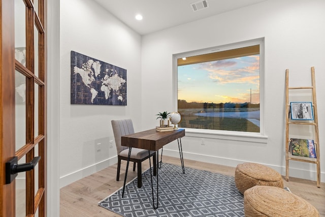 office area featuring light hardwood / wood-style floors and a water view