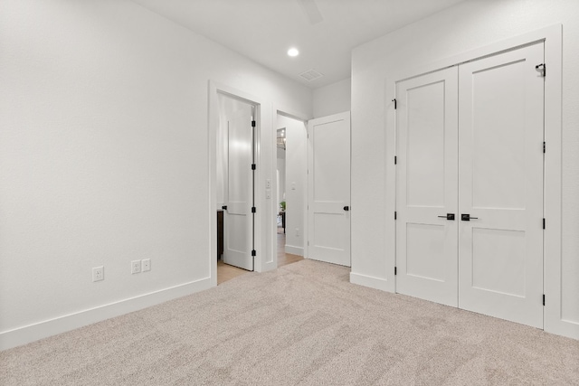 unfurnished bedroom with ceiling fan, light colored carpet, and a closet