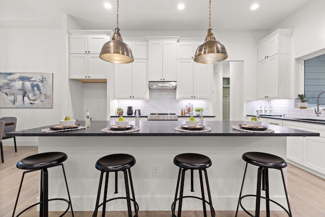 kitchen featuring white cabinetry, decorative light fixtures, sink, and a kitchen island