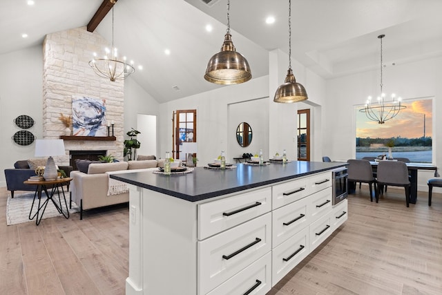 kitchen featuring white cabinetry, a fireplace, decorative light fixtures, and high vaulted ceiling