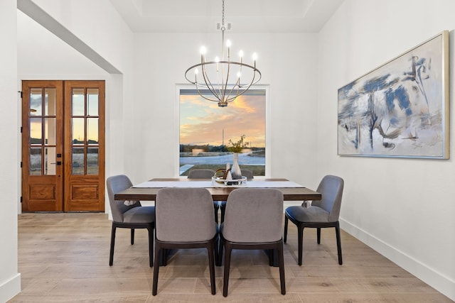 dining room featuring french doors, a chandelier, and light hardwood / wood-style flooring